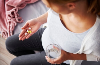 Schwangere Frau nimmt verschiedene Tabletten ein